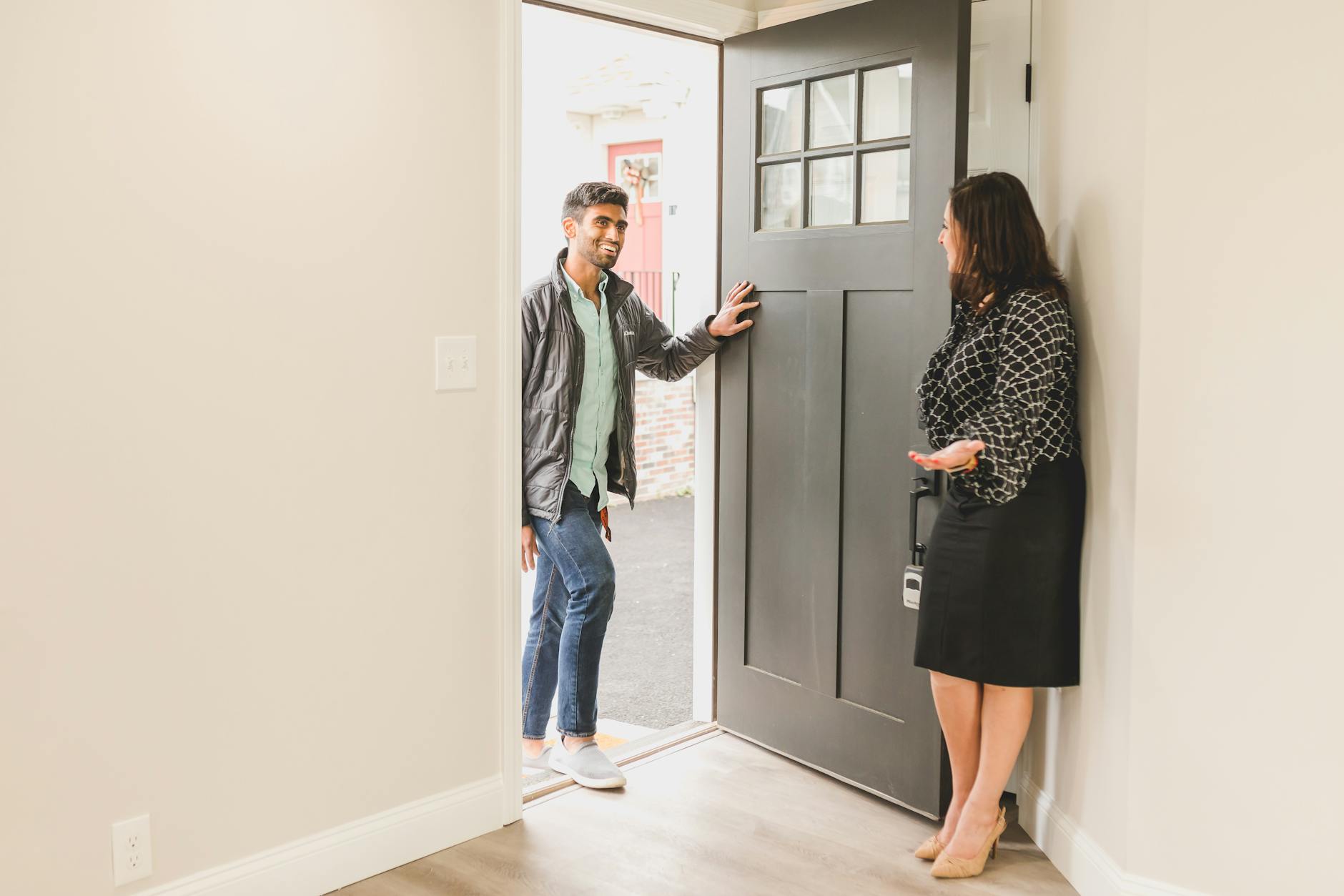 Real estate agent greeting a client at the entrance of a new home, symbolizing a welcoming embrace for potential buyers.