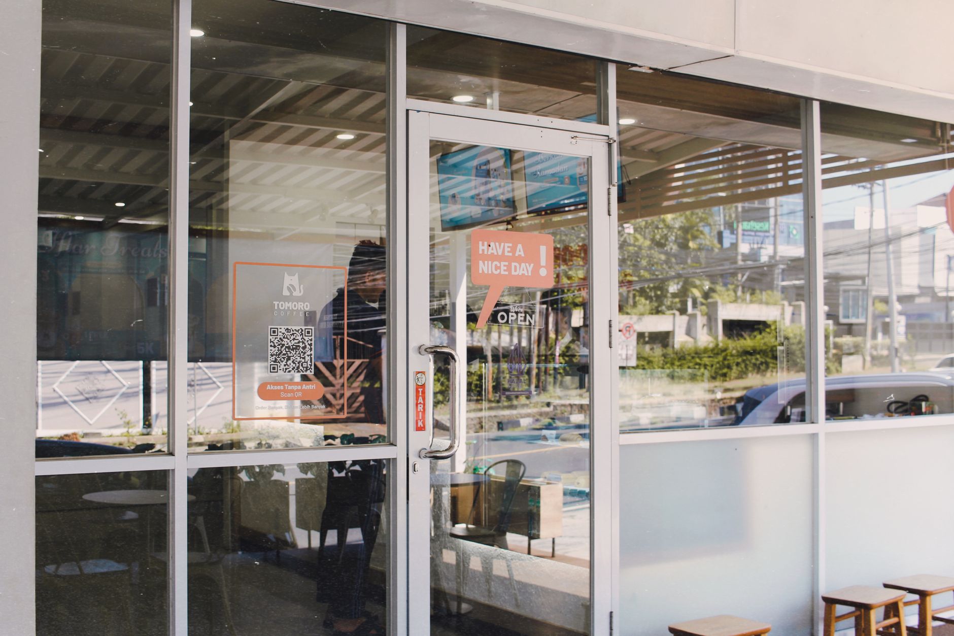 Glass door entrance to a cafe with signage reading 'Have a Nice Day'.