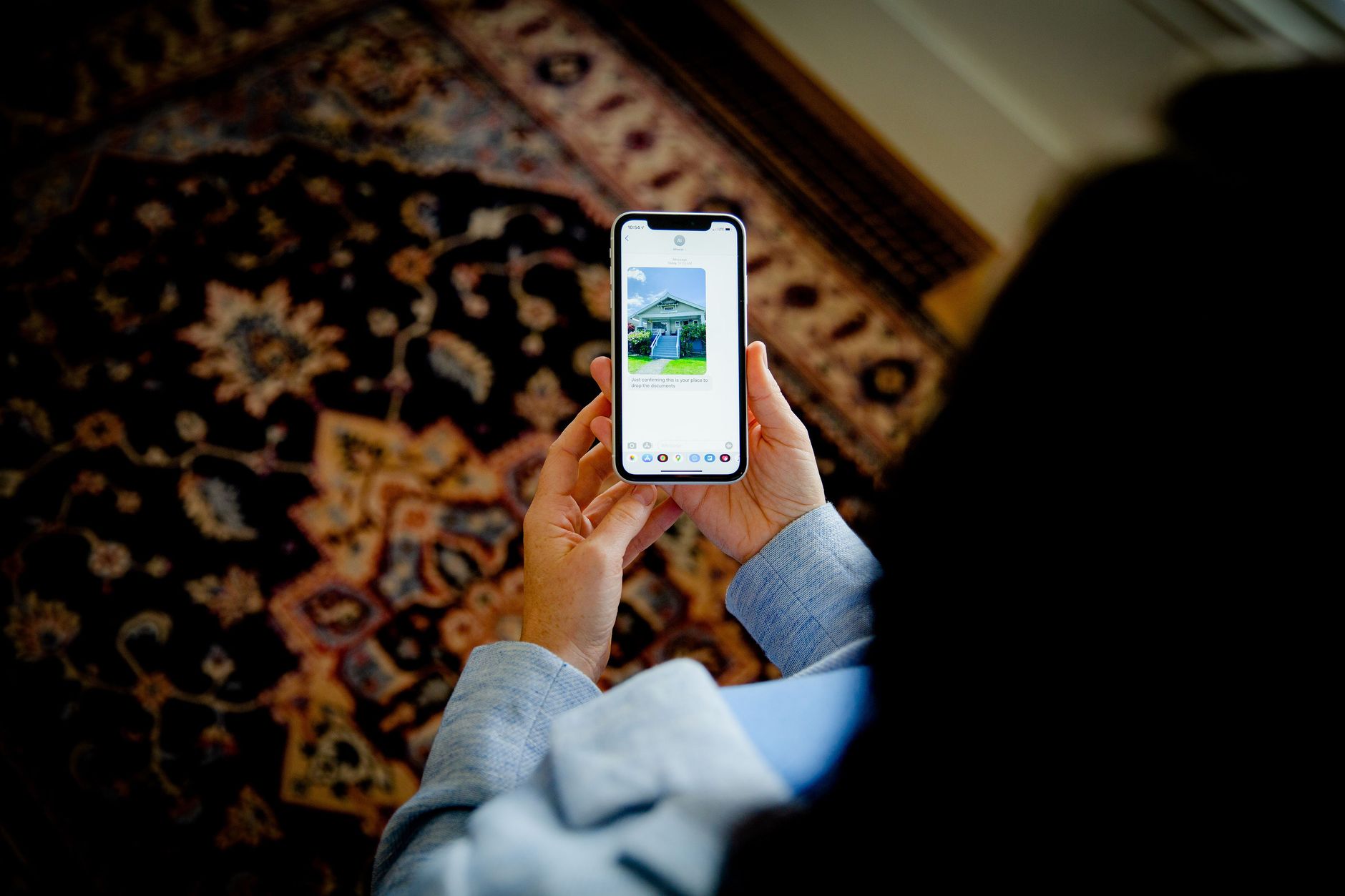 Overhead view of a person using a smartphone to view a photo of a home indoors