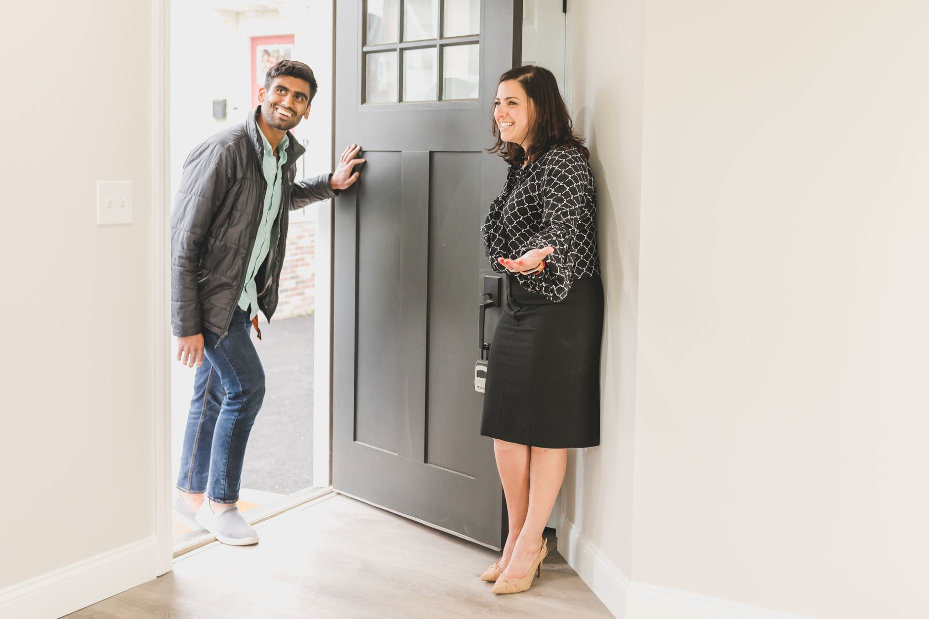 Friendly real estate agent welcoming potential homebuyer at an open house.